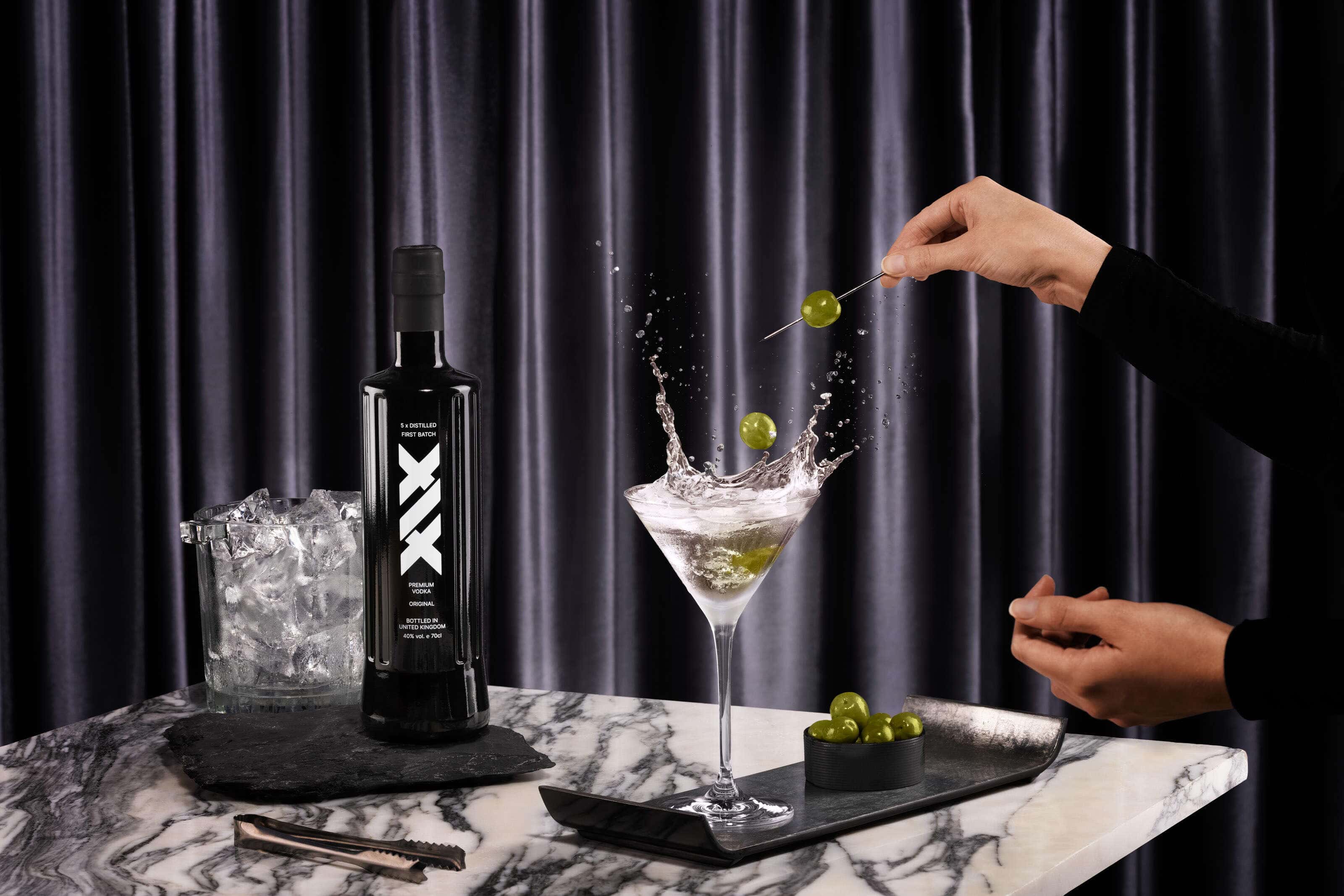 xix vodka martini with olives splashing into the drink