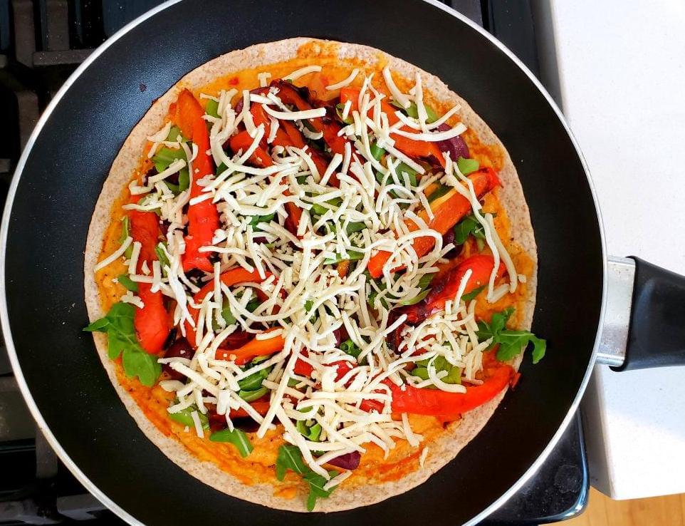 Open-face quesadilla with hummus, vegan cheese, and vegetables