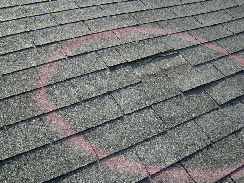Roofing shingles with circle indicating damage