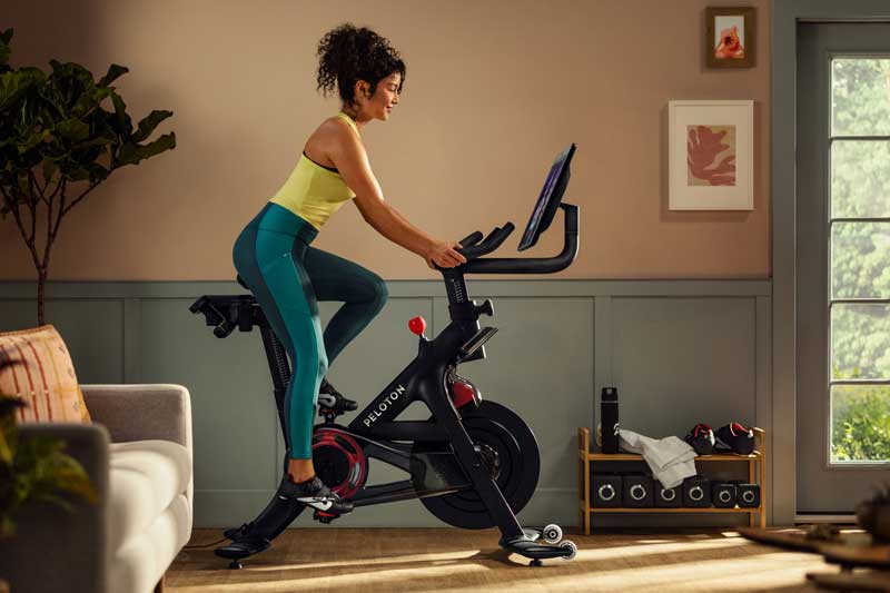 Photo of a woman riding a Peloton exercise bike in a family room.