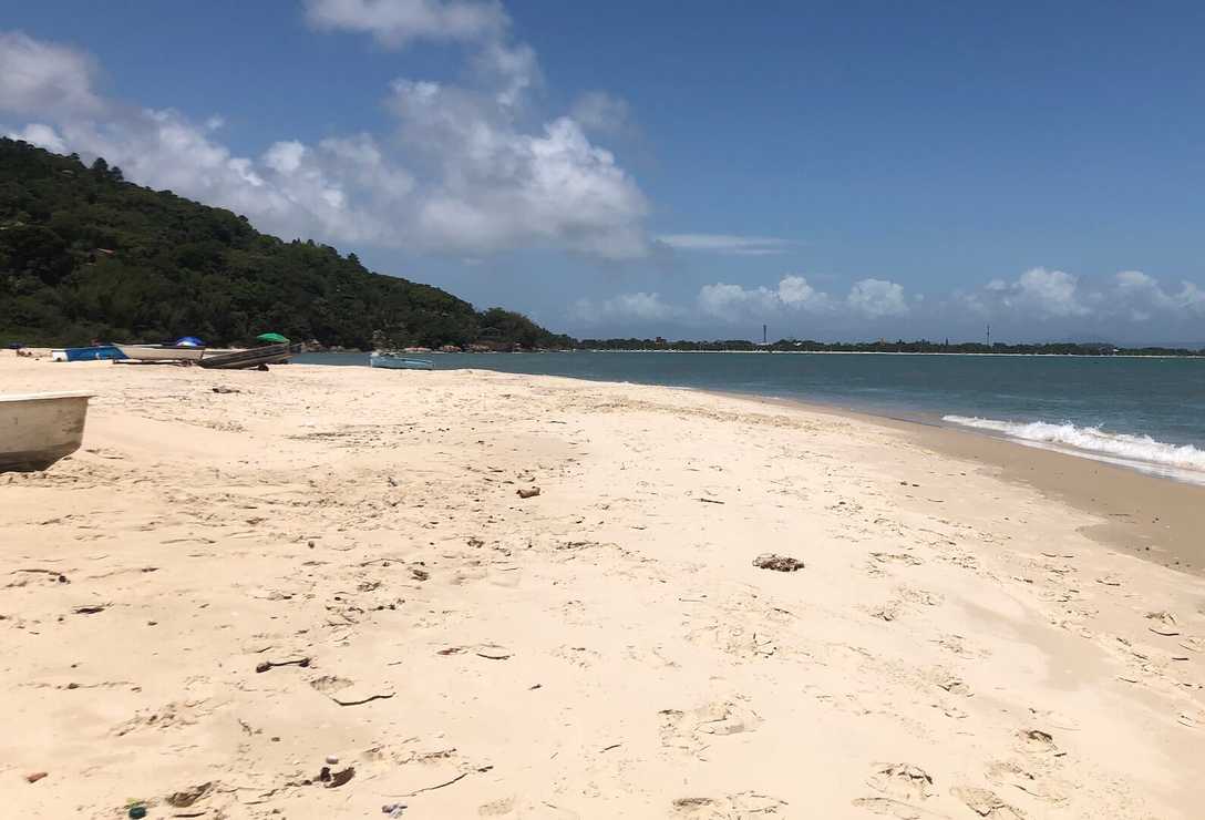 Vista do mar com faixa de area a esquerda, ao fundo o céu.