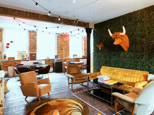 Alternative style meeting room with artistic decoration and wooden flooring containing assorted styled seating Zoom background