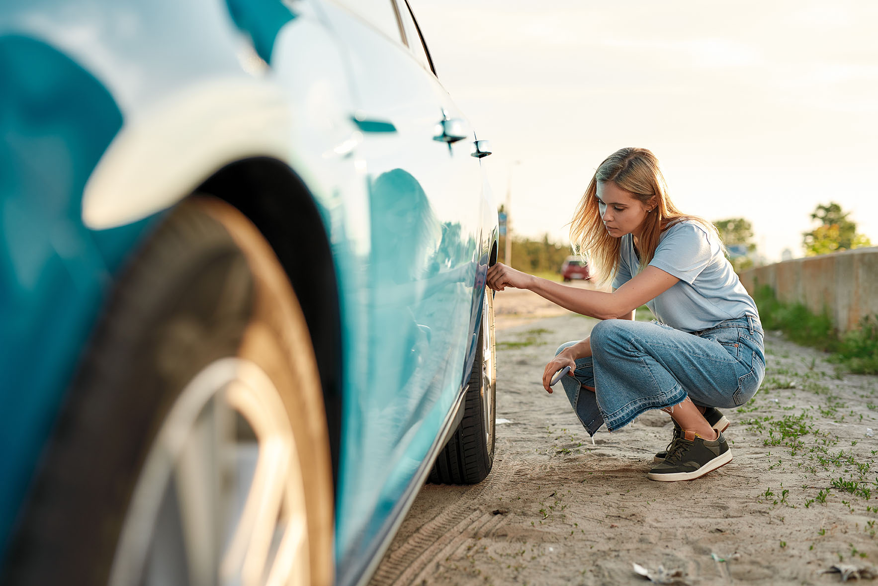 Woman checking the tire pressure on her car
