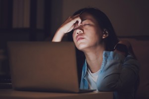 Asian woman student or businesswoman work late at night. Concentrated and feel sleepy at the desk in dark room with laptop or notebook.Concept of people workhard and burnout syndrome. stress vagina health