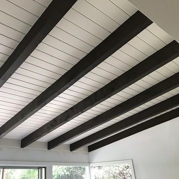 brown stained pillars holding up a white shiplap ceiling