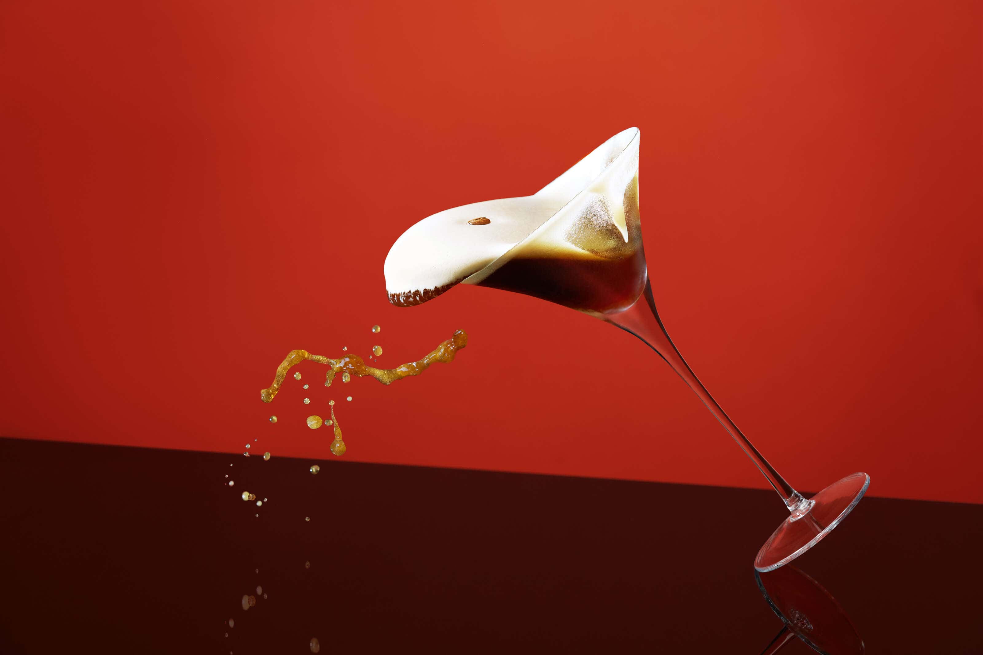espresso_martini_splashing out of glass onto perspex with red background