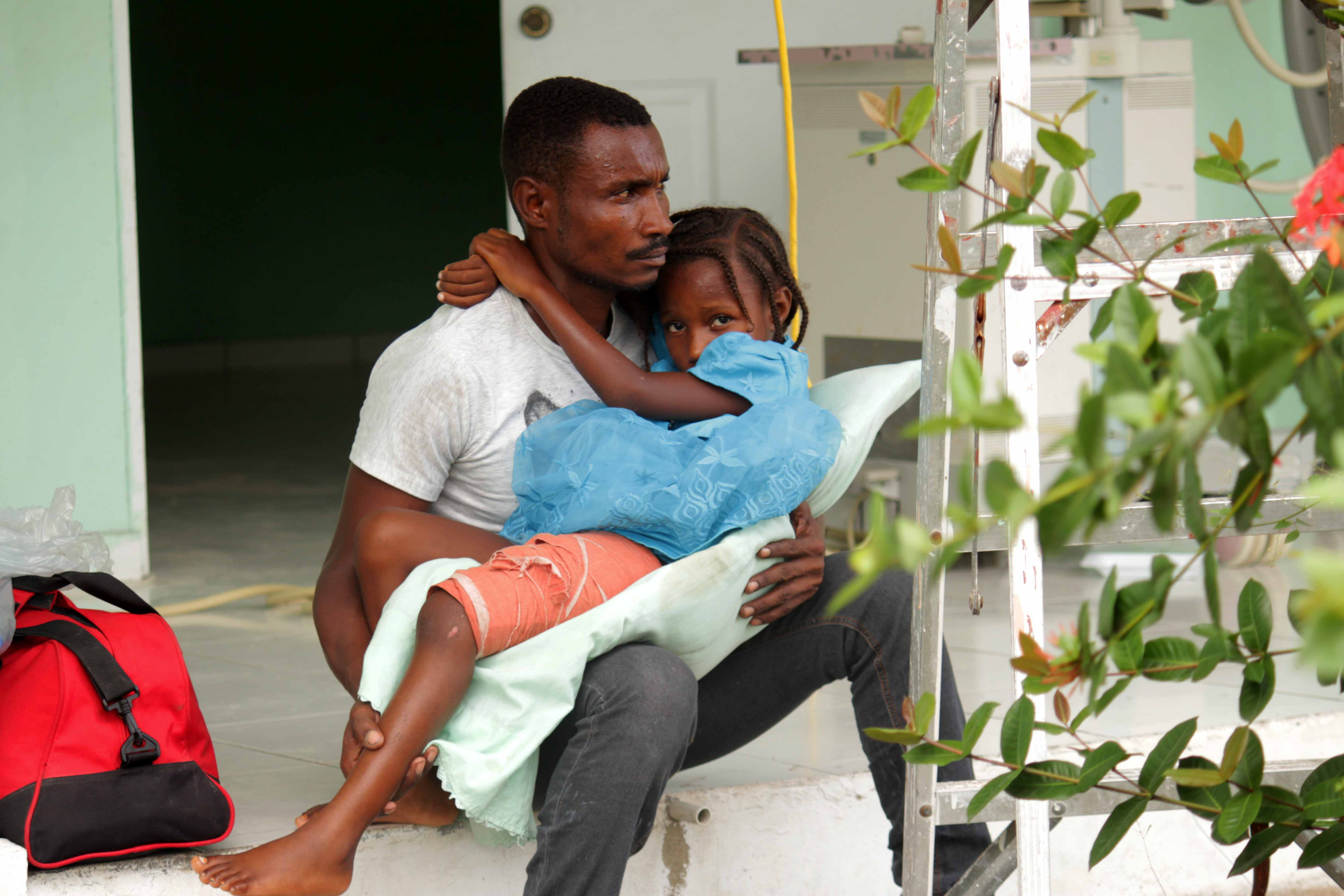 A 6-years-old girl sits with her father while waiting for medical care at the general hospital of Les Cayes, Haiti following the August 2021