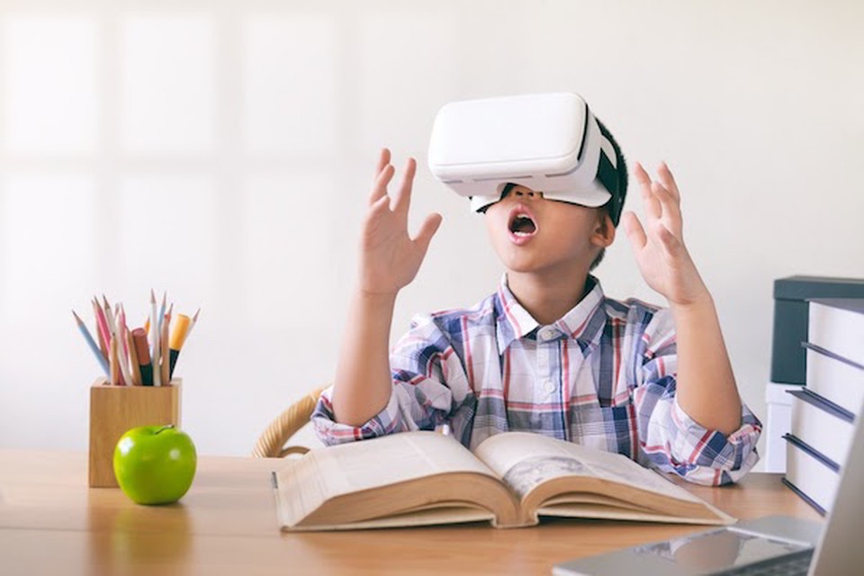 A young male student uses a VR headset at school, enjoying the benefits of virtual reality in education.