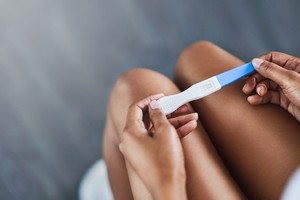 Cropped shot of a young woman taking a pregnancy test at home