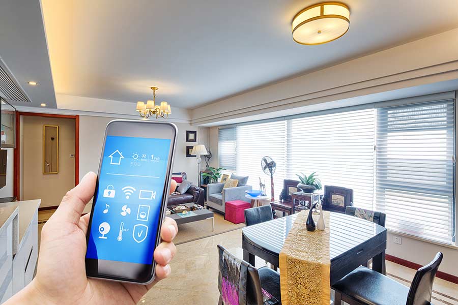 Hand holding a phone with apps to connect to several smart devices in a home