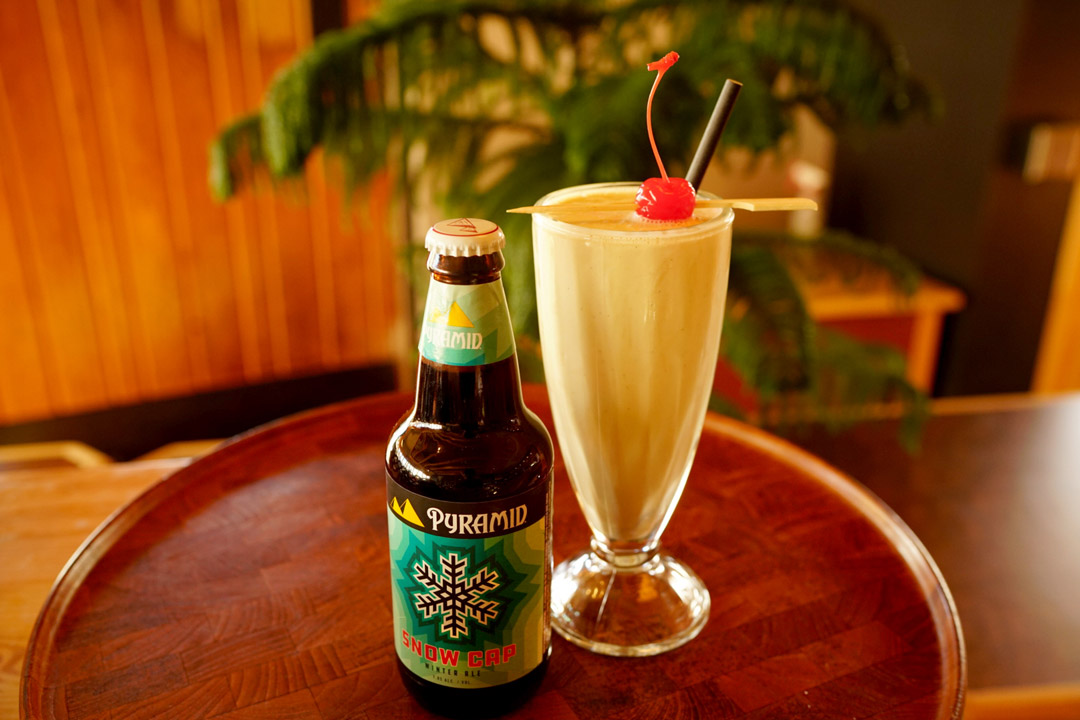 Beer cocktail with ice cream dark drum brandy and kahlua Bottle of Pyramid Snow Cap next to ice cream shake beer cocktail on a small table
