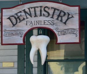 An old-looking sign that reads 'Dentistry - Painless - Extractions - Dentures