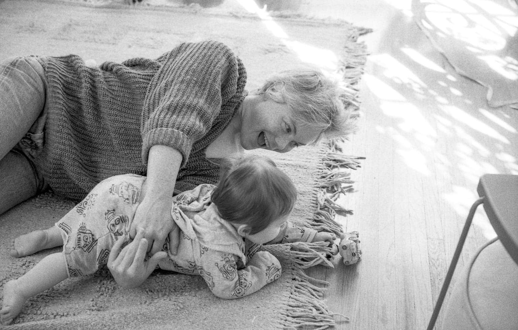 A woman and child playing on a living room floor