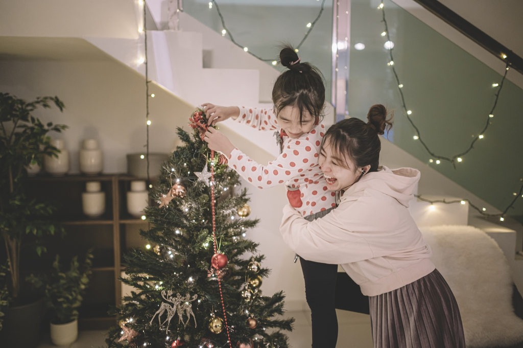 Family decorating a Christmas tree at home