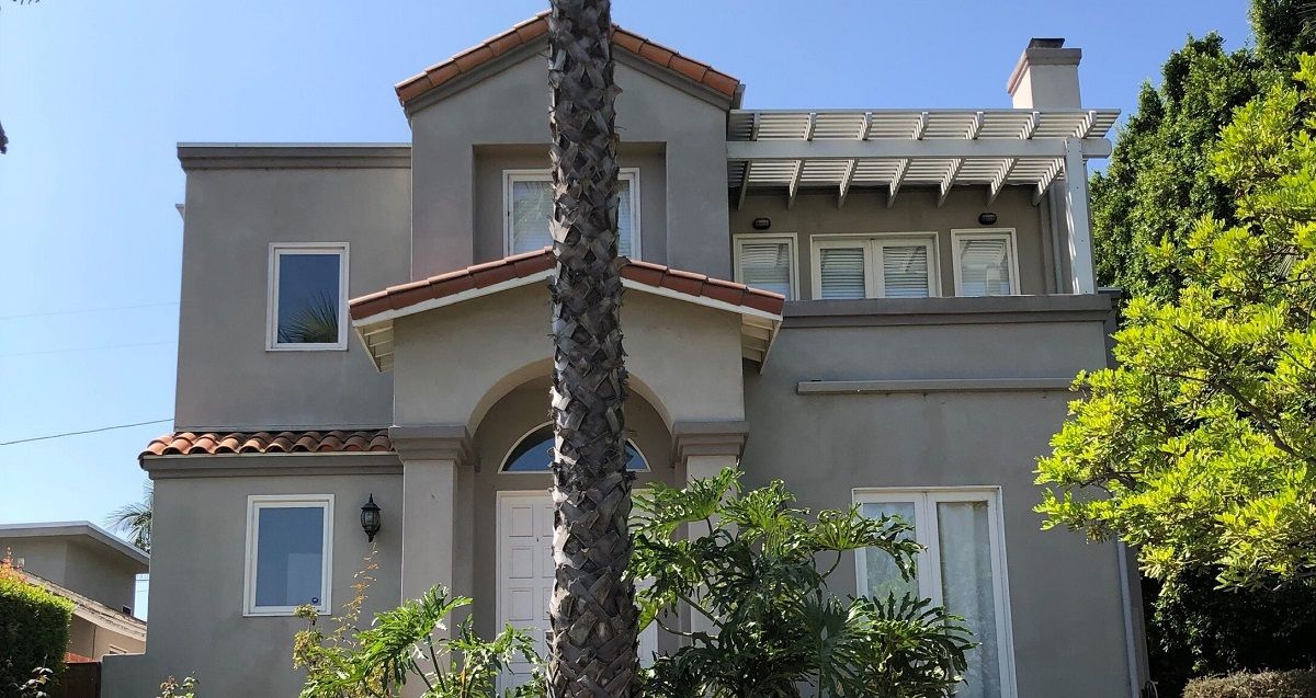 enlarged photo of light grey stucco home with a dark brown ceramic roof