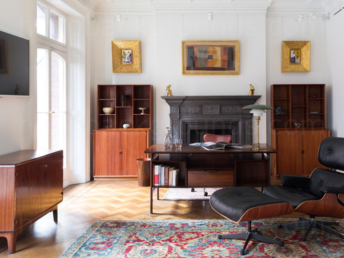 Large traditional private office with wooden furnishings and wall mounted art pieces Zoom background