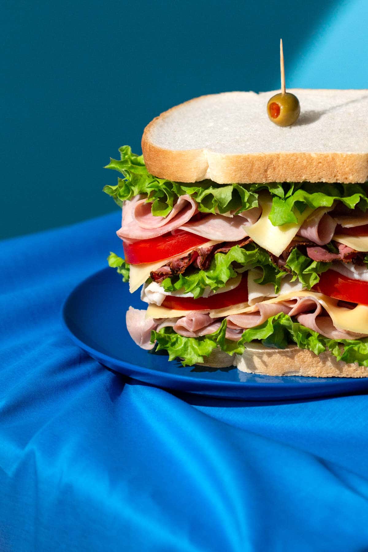 ham and pastrami cheese sandwich shot in a pop art style with blue props