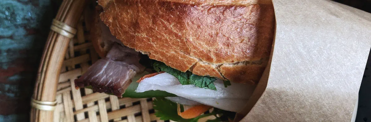 A banh mi sandwich with French bread, beef, cucumber, cilantro, daikon radish, and carrots