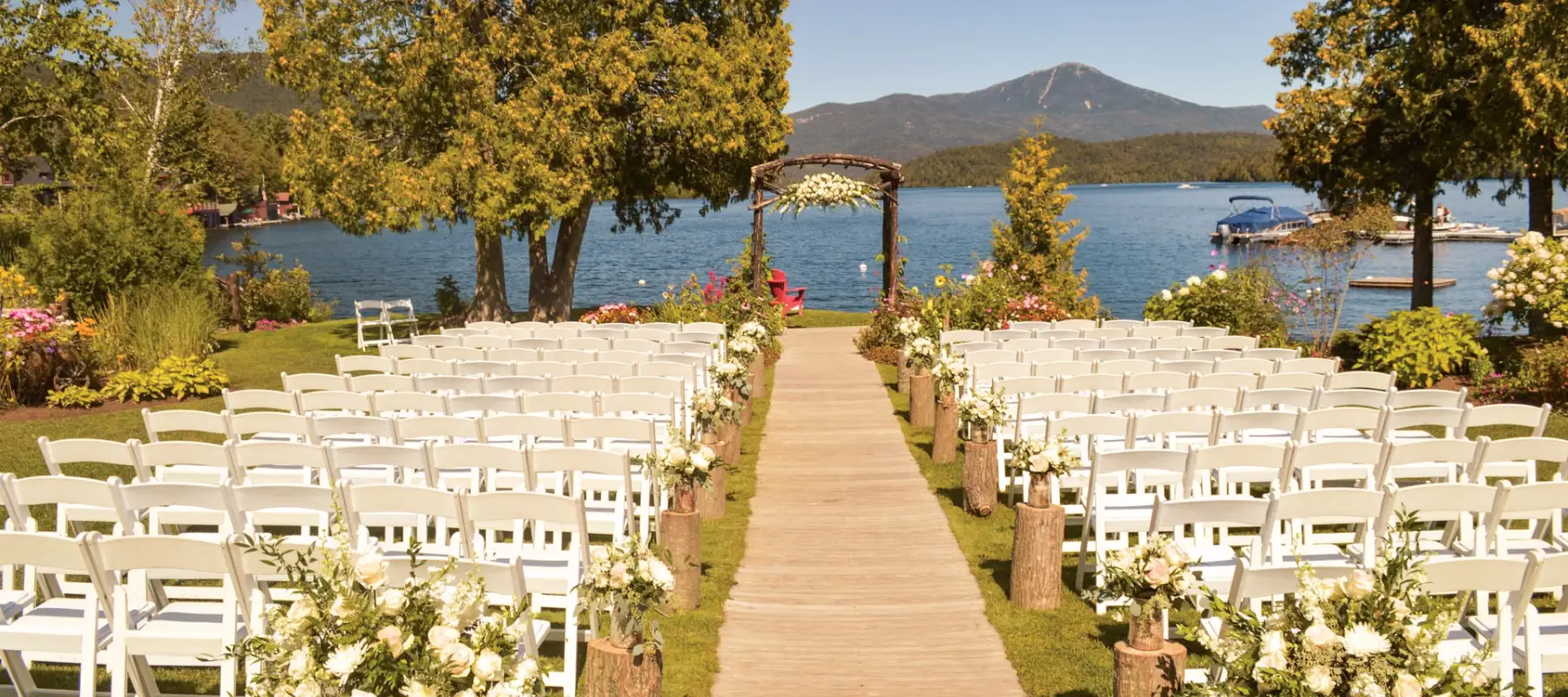 Foto de cadeiras organizadas em fileiras diante de um altar de casamento em um gramado com uma praia ao fundo