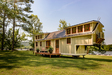 Timbercraft Tiny Homes' Denali gooseneck tiny house; exterior picture showing the large tiny home with porch area, two dormer bedrooms and black roof with light-cream walls. Timbercraft Tiny Homes' Denali gooseneck tiny house; exterior picture showing the large tiny home with porch area, two dormer bedrooms and black roof with light-cream walls.