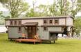 Timbercraft Tiny Homes' Retreat gooseneck tiny house; exterior photo showing the blue-gray cladding and covered porch area with double doors Timbercraft Tiny Homes' Retreat gooseneck tiny house; exterior photo showing the blue-gray cladding and covered porch area with double doors