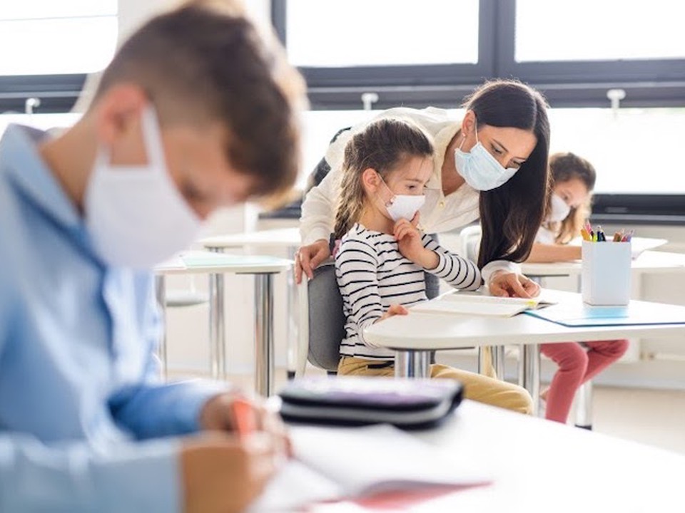 Teacher and students wearing face masks in a classroom.
