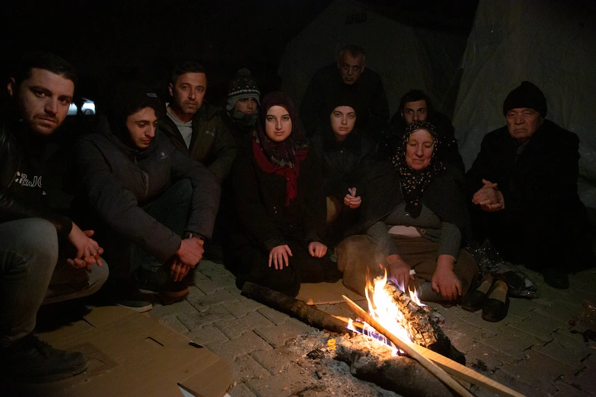 A family stays warm by a fire after the 2023 Turkey earthquake