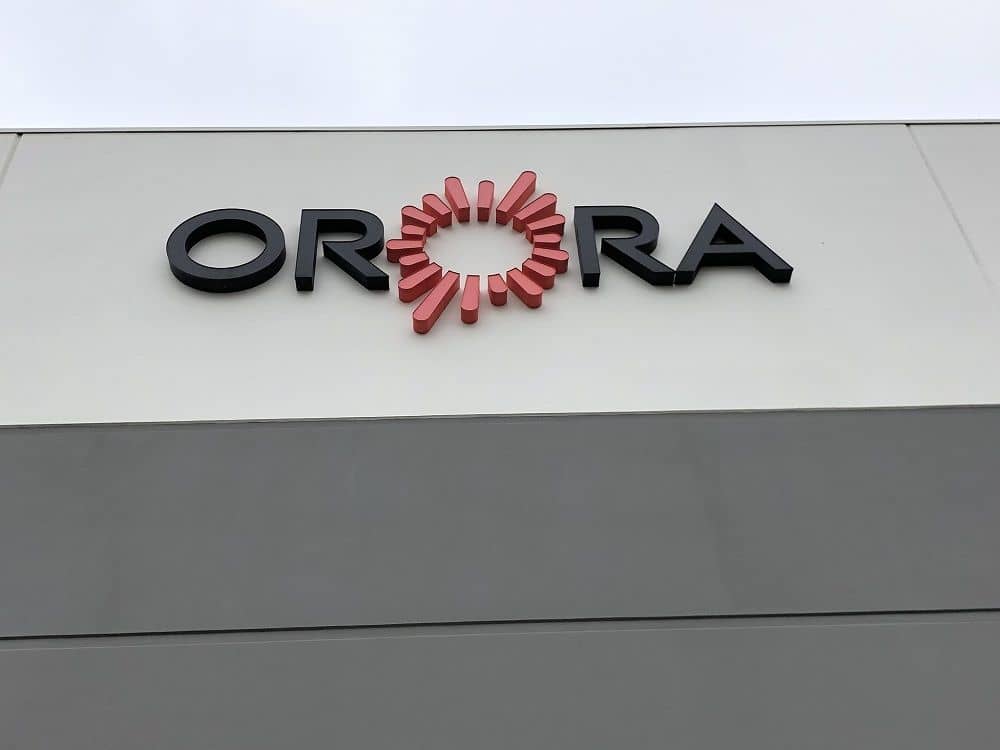 enlarged photo of logo of a company called orora against newly painted grey exterior walls