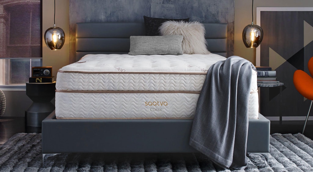 Saatva mattress on a grey bed in a dim-lit cozy room
