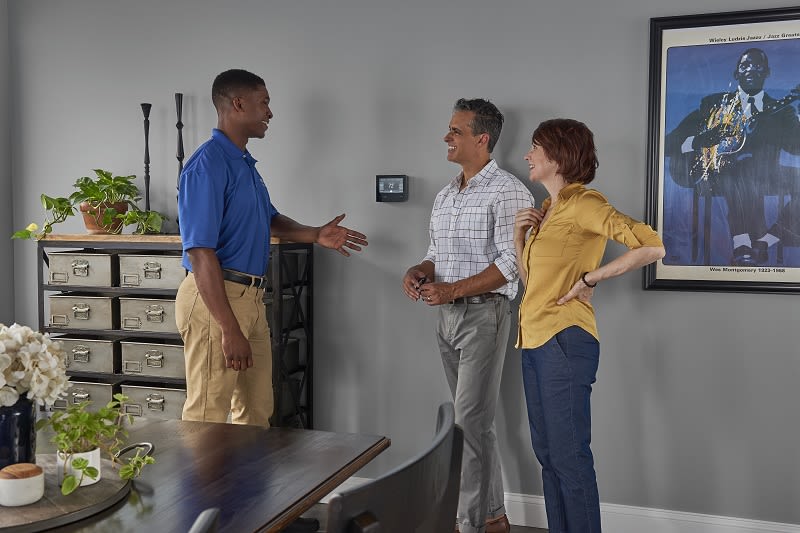 Carrier technician explaining a wifi thermostat to a younger couple