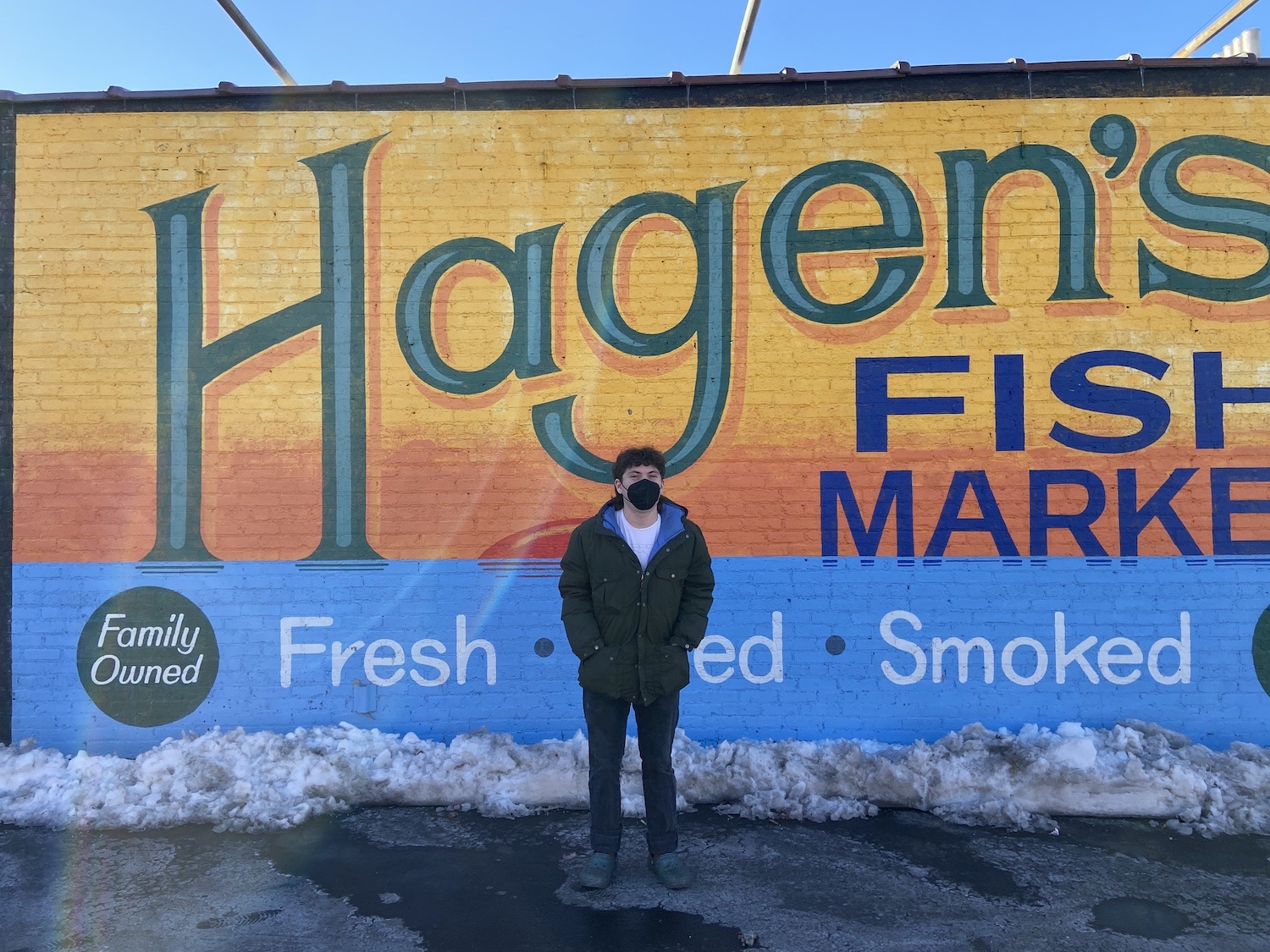 Sammy standing in front of the brick wall mural at Hagen's Fish Market.