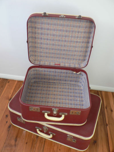 Two vintage suitcases stacked on each other, with the top one wide open and empty.