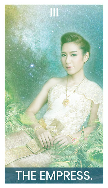 The Empress card. A woman ina formal dress lounges on a throne. The universe is at her back, and nature at her feet.