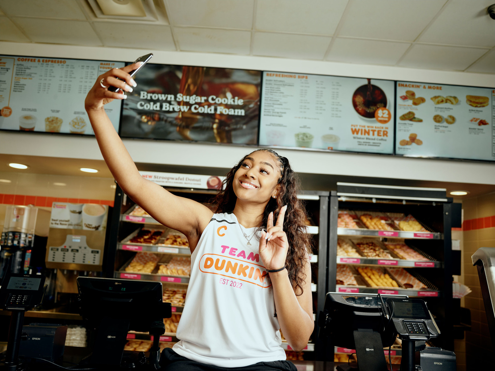 Deja Kelly taking a selfie for Instagram inside a Dunkin’