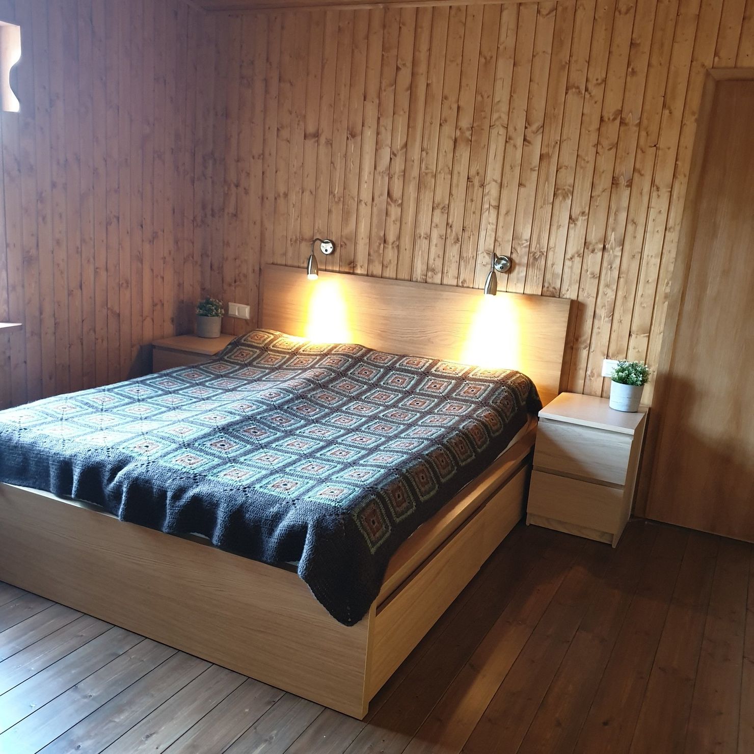 Holzverkleidetes Schlafzimmer mit großem Doppelbett
