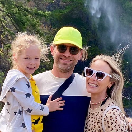 Mark, his daughter, and wife smiling with a waterfall in the background.