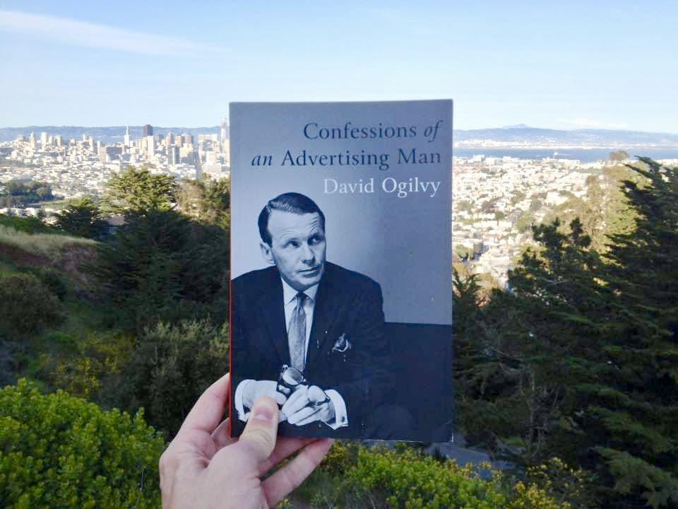 The book held up against a backdrop of nature and an urban skyline.