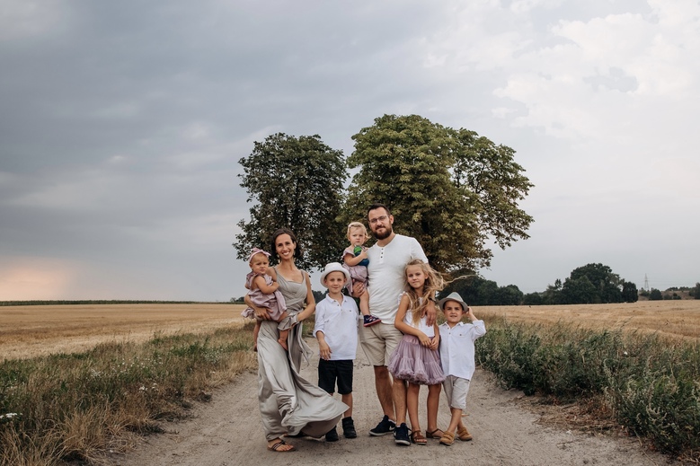 Sesja rodzinna Poznań - rodzice z pięciorgiem dzieci w Strzeszynku na tle pola