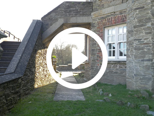 Traditional stone house entrance with stone steps and bridge-like path with grass lawn below Zoom background