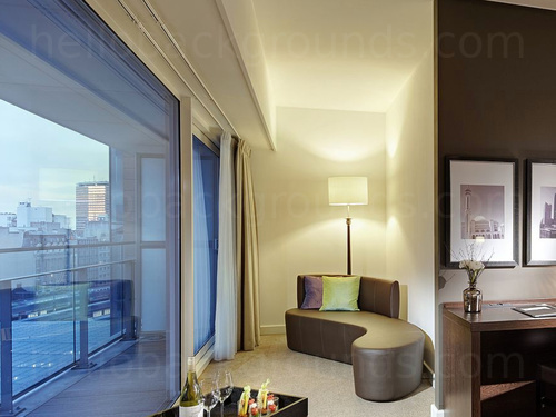 Compact private office with city views featuring sleek wooden desk and contemporary style chaise lounge Google Meet background