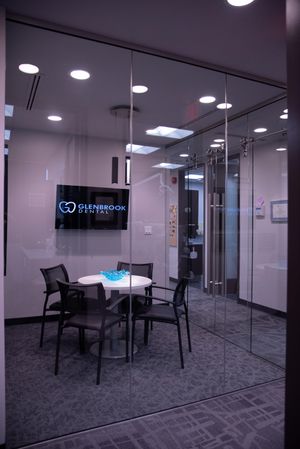 A glass-enclosed meeting room at Glenbrook Dental with a meeting table and a screen on the wall