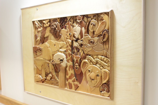 A wall hanging of multiple wood animal faces at various depths and in various wood stains. You can feel the heads of a tiger, a rhinoceros, a flamingo, giraffe, and many more.