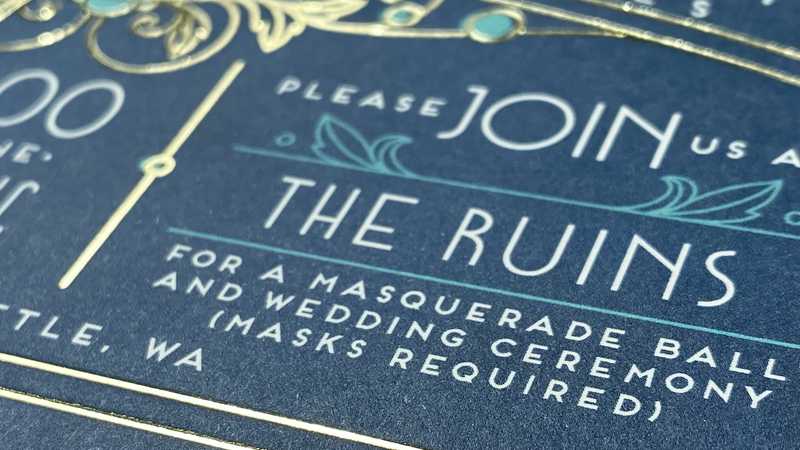 Part of a wedding invite. The visible section reads "Please join us at THE RUINS for a masquerade ball and wedding ceremony (masks required)"