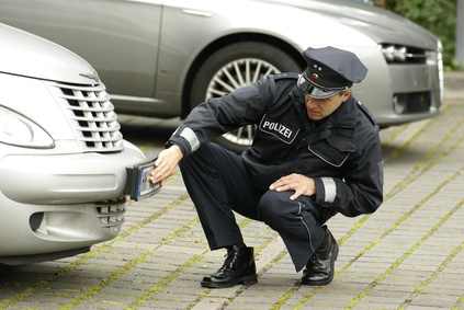 Polizist untersucht Schaden nach Verkehrsunfallflucht.