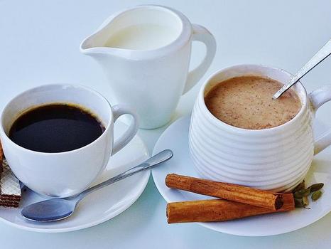 Chai mit Zimtstangen und Kardamon sowie Kaffee mit Milchkännchen und Waffel, liebevoll serviert