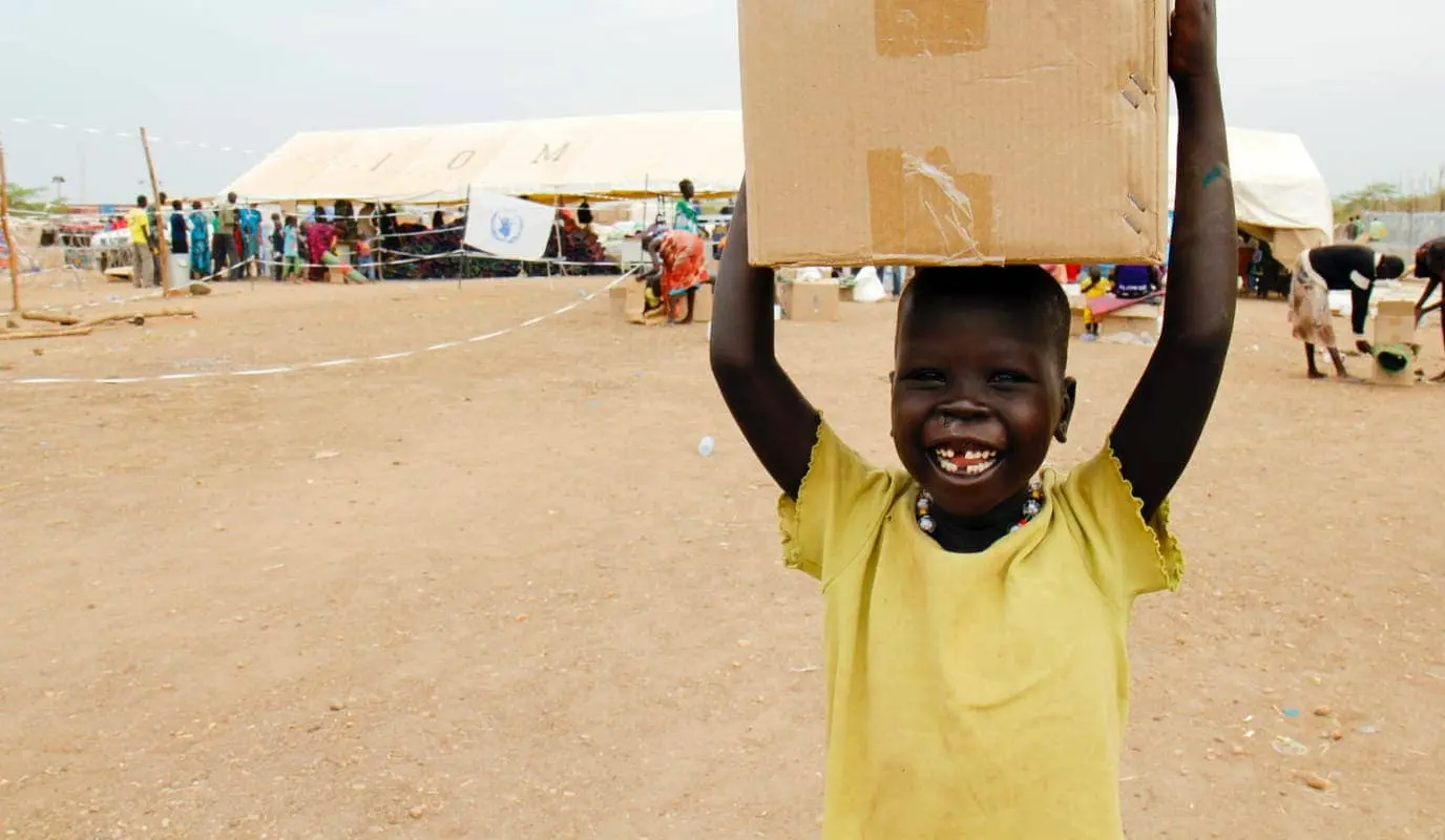 A child with food, supplies, and water from Concern Worldwide and other humanitarian organizations in Tomping, a UN base.