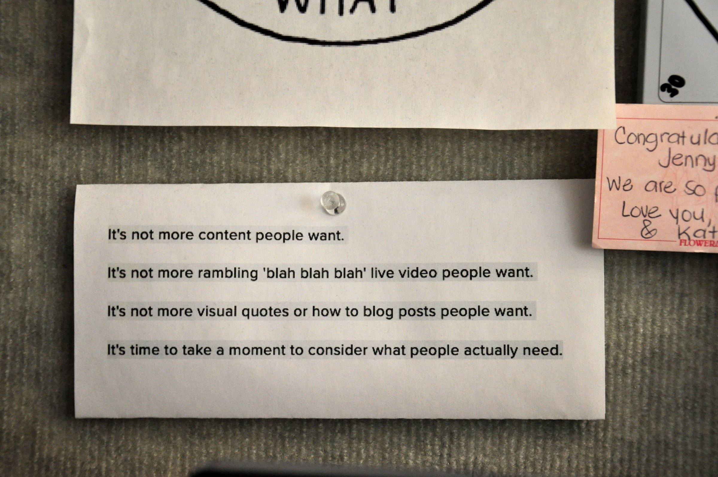 Sticky note on board with message “It’s not more content people want, it’s time to take a moment to consider what people actually need”