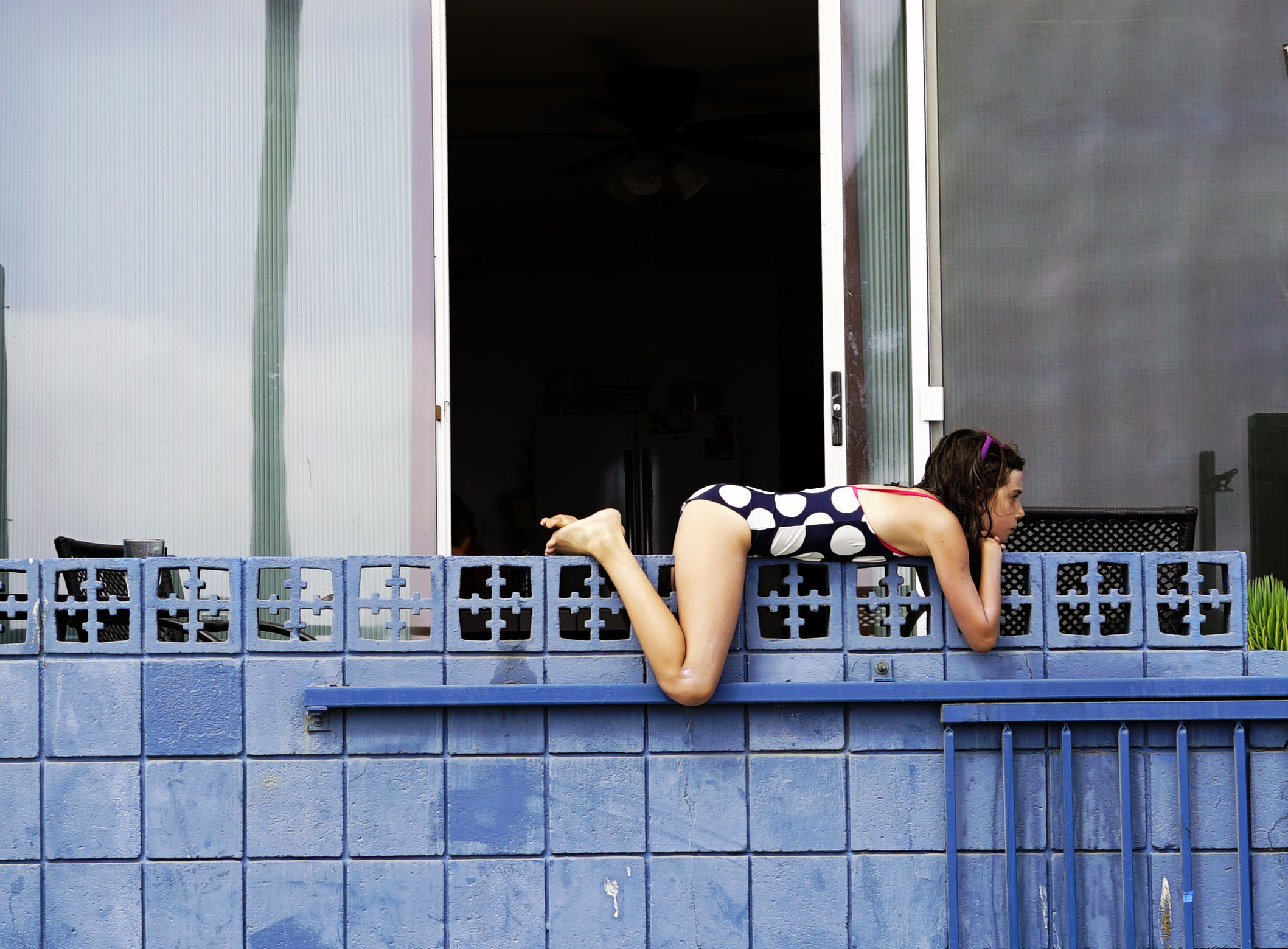 girl in swimsuit resting on a blue wall