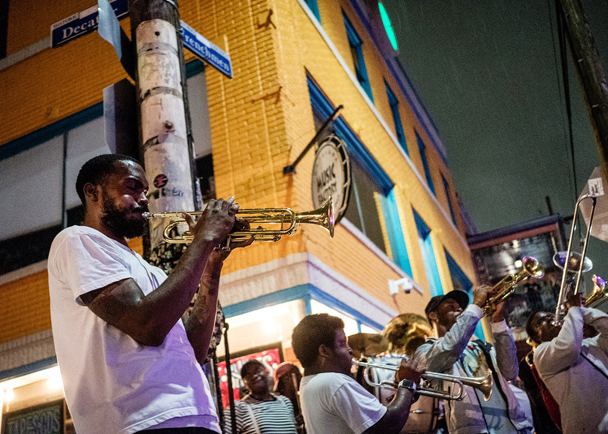 black man playing the trumpet at night on a street corner in new orleans
