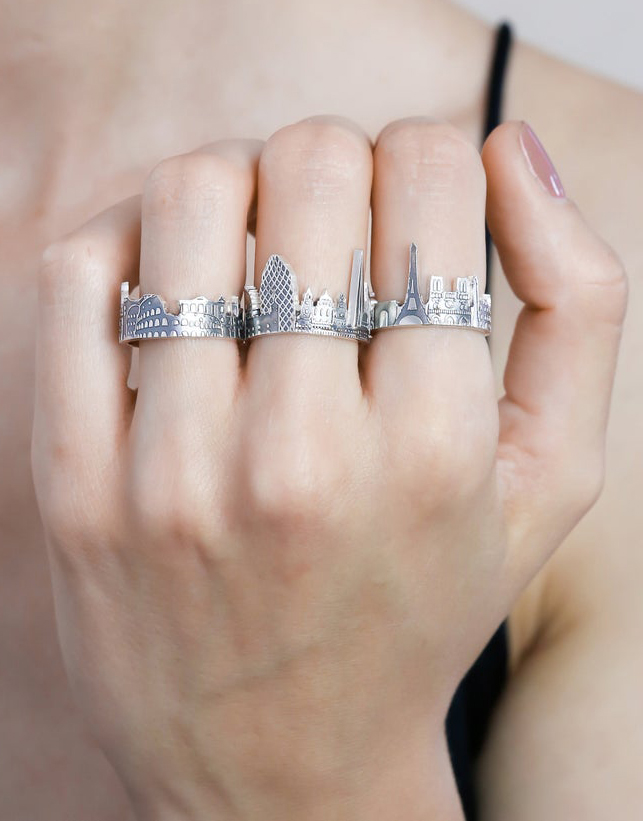 hand wearing silver rings in the shape of city skylines